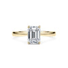 0.50ct emerald cut diamond solitaire engagement ring set in gold.  The diamond's sleek, rectangular shape with trimmed corners is set in a simple, elegant band, enhancing its clean lines and sophisticated sparkle.